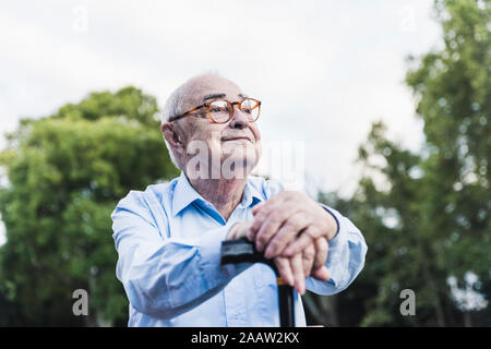 Portrait von älteren Menschen in einem Park lehnte sich auf seinen Gehstock Stockfoto