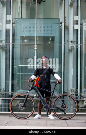 Stilvolle Junger Mann mit Fahrrad und Messenger Bag in der Stadt Stockfoto