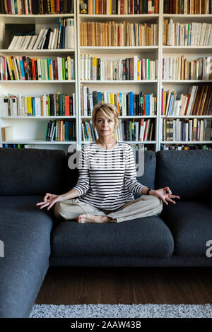 Reife frau yoga auf der Couch zu Hause Stockfoto