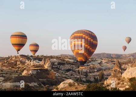 Bunte Heißluftballone fliegen über Landschaft gegen klare Himmel in Kappadokien, Türkei Stockfoto