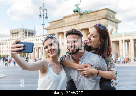 Portrait von drei Freunden, die selfie mit Handy vor dem Brandenburger Tor, Berlin, Deutschland Stockfoto