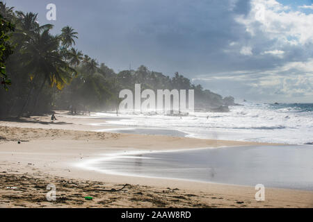 Malerische Aussicht auf Wellen plätschern am Ufer gegen bewölkter Himmel auf Trinidad und Tobago, Karibik Stockfoto