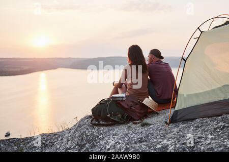 Foto von glücklichen Paare im Zelt sitzen mit Blick auf den See während der Wanderung. Reisen Abenteuer Urlaub Konzept Stockfoto
