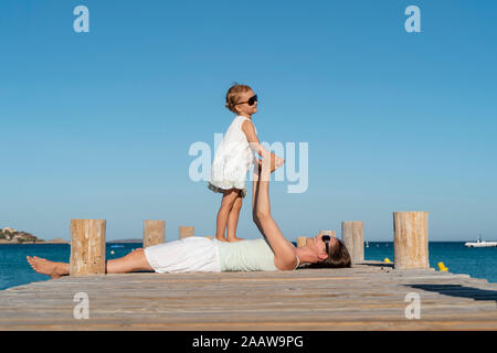 Glückliche Mutter mit Tochter auf einem Steg am Meer Stockfoto