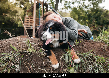 Junge spielt mit seinem Berner Sennenhund im Garten Stockfoto