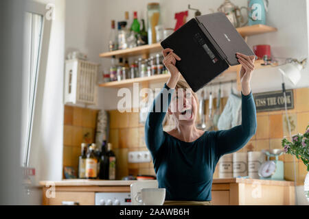 Portrait von schreienden Frau mit Laptop in der Küche Stockfoto