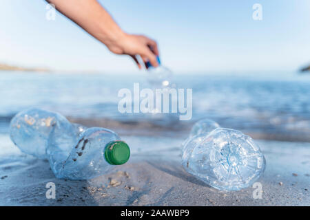 Hand sammeln von leeren Plastikflaschen an der Küste Stockfoto