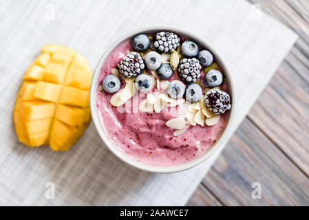 Gesundes Frühstück Berry Smoothie Schüssel gekrönt mit Blaubeeren, Brombeeren, Kürbiskerne und Mandelflocken mit Copyspace. Lecker mango Smoothie b Stockfoto