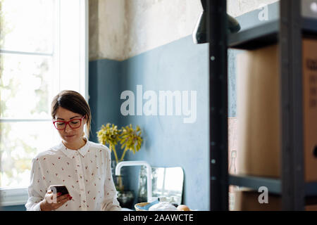 Frau mit Smartphone im Büro kitchenet Stockfoto