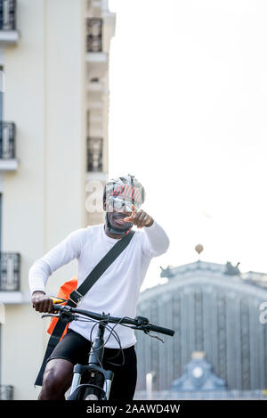 Stilvolle Junger Mann mit Fahrrad und Messenger Bag in der Stadt seinen Finger Stockfoto