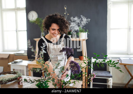 Lächelnden jungen Frau, die die Blumen in einem kleinen Laden Stockfoto