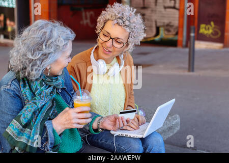 Ältere Mutter mit ihrer erwachsenen Tochter Einkaufen online zusammen in der Stadt Stockfoto