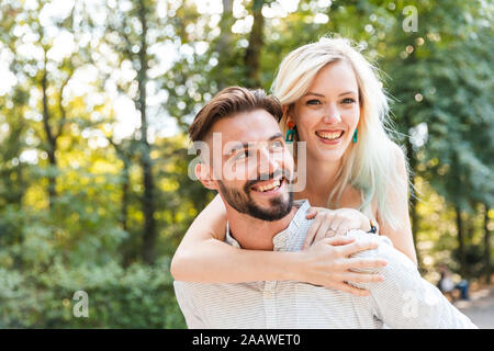 Porträt der glückliche junge Mann seine Freundin eine piggyback Ride geben Stockfoto