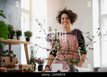 Portrait von lächelnden jungen Frau in einem kleinen Laden mit Pflanzen Stockfoto