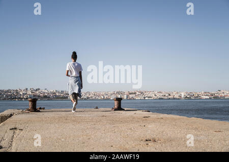 Junge Frau zu Fuß auf Pier an der Waterfront, Lissabon, Portugal Stockfoto