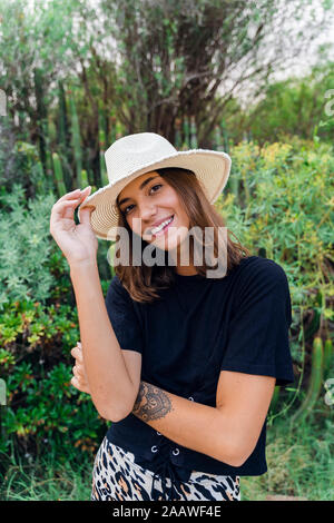 Portrait von lächelnden jungen Frau mit Tattoo tragen Sommer hat in der Natur Stockfoto