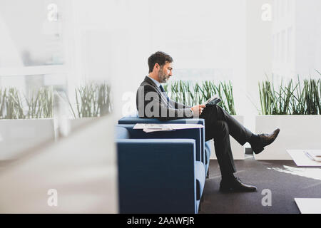 Reifen Geschäftsmann im Wartebereich lesen Magazin sitzen Stockfoto