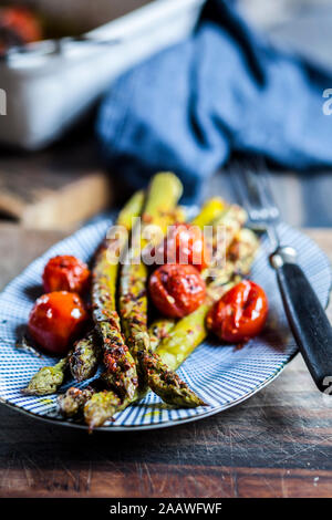 Gegrillter grüner Spargel mit Kirschtomaten auf einer Platte Stockfoto