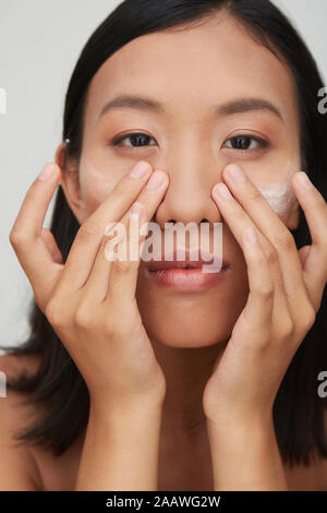 Porträt der jungen weiblichen chinesischen Frau Anwendung Creme Stockfoto