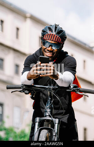 Stilvolle Junger Mann mit Fahrrad, Smartphone und Messenger Bag in der Stadt Stockfoto