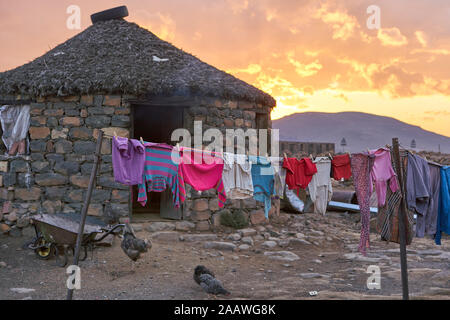 Sonnenuntergang in einem typischen Haus mit hängenden Kleidungsstücken, Lesotho, Afrika Stockfoto