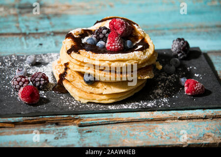 Nahaufnahme der Pfannkuchen mit Schokoladensauce und verschiedenen Beeren auf Tisch Stockfoto