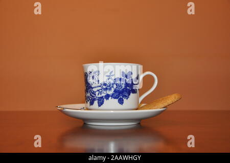 Elegante Porzellan Kaffeetasse auf Holztisch, eine weiße Porzellan Schale mit blauen Blumen Stockfoto