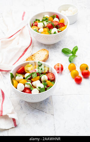 Serviette, Scheiben Brot und zwei Schalen mit frischem Salat liegen auf Fliesen- Tabelle Stockfoto