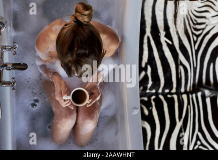 Frau in ein entspannendes Bad und eine Tasse Kaffee in der Badewanne. Stockfoto