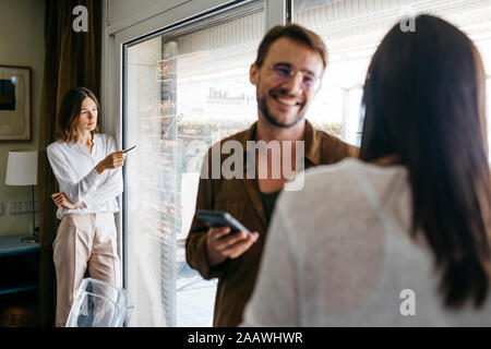 Frau schreiben auf Glasscheibe mit Kollegen im Vordergrund. Stockfoto