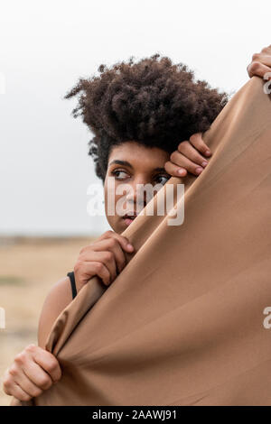 Porträt der jungen Frau hinter Tuch halten Sie von vier Händen Stockfoto