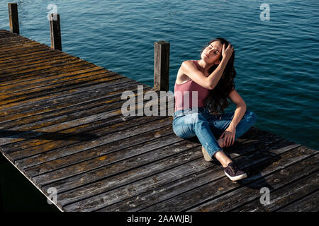 Junge Frau mit geschlossenen Augen direkt am Bootsanleger, Starnberger See, Deutschland Stockfoto