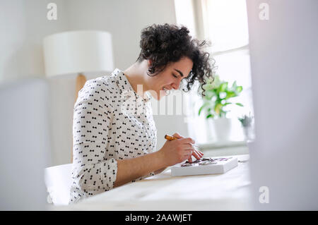 Lächelnde junge Frau am Tisch arbeiten Stockfoto