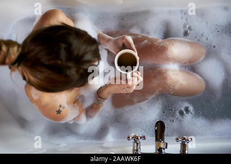 Frau in ein entspannendes Bad und eine Tasse Kaffee in der Badewanne. Stockfoto