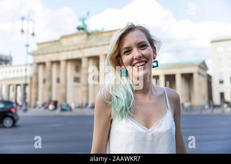 Portrait von lächelnden jungen Frau vor dem Brandenburger Tor, Berlin, Deutschland Stockfoto