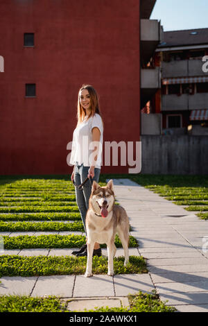 Porträt der glückliche junge Frau, die mit Ihrem Hund Gassi am Abend Stockfoto