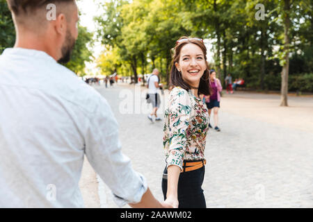 Porträt der glückliche junge Frau, die Hand in Hand mit ihrem Freund in einem Park Stockfoto