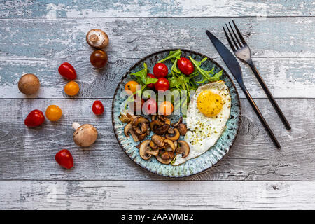 Low carb Frühstück mit Spiegelei, Champignons, Rucola und Tomaten/Paradeiser Stockfoto