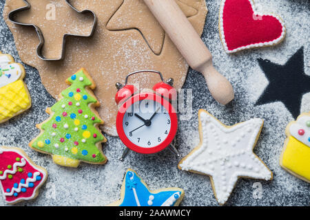 Flach für Weihnachtsplätzchen Vorbereitung Konzept aus Schneider, Teig, Nudelholz, Kekse mit bunten Vereisung und Wecker auf Tisch. Stockfoto