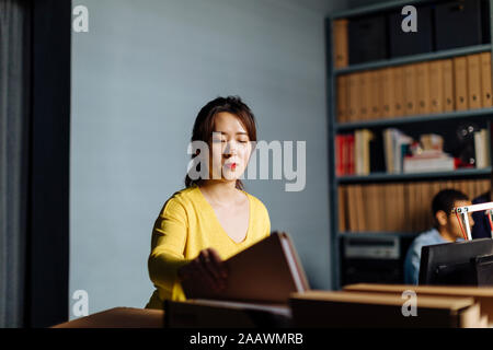 Junge Frau von Dateien im Office suchen Stockfoto