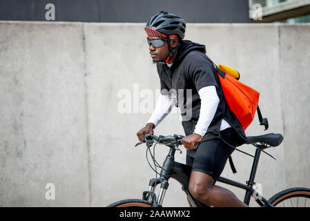 Stilvolle junger Mann mit messenger bag Reiten Fahrrad in der Stadt Stockfoto