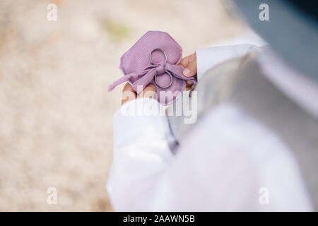 Mittelteil des Kindes halten Hochzeit Ringe beim Stehen im Freien Stockfoto