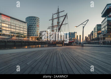 Schiff im Hafen gegen Himmel bei Sonnenuntergang in der HafenCity, Hamburg, Deutschland Stockfoto