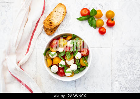 Serviette, Scheiben Brot und Schale mit frischem Salat liegen auf Fliesen- Tabelle Stockfoto