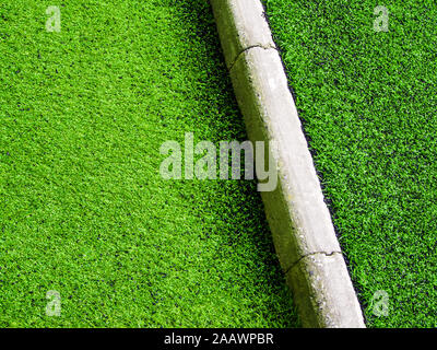 Textur aus Kunststoff künstliche Gras und die konkrete Grenze von Schulhof Stockfoto
