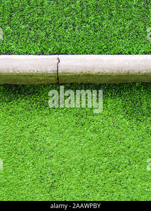 Textur aus Kunststoff künstliche Gras und die konkrete Grenze von Schulhof Stockfoto