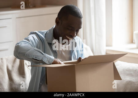 Happy biracial Mann Paket online Einkaufen auspacken Stockfoto