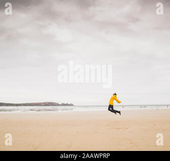 Junge Frau tragen gelbe Regenjacke am Strand, Bretagne, Frankreich Stockfoto