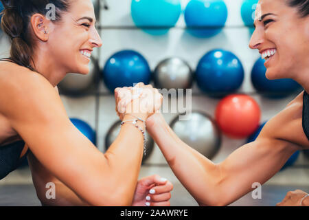 Gerne weibliche Zwillinge in guter Form tun, Arm Wrestling Herausforderung in einer Turnhalle Stockfoto