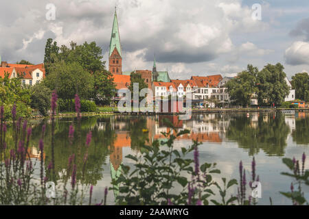 Häuser und St. Aegidien-Kirche von krähenteich See gegen bewölkten Himmel in Lübeck, Deutschland Stockfoto